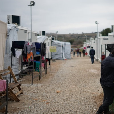 In einem Flüchtlingslager. Auf den Wegen hängt Wäsche zum Trocknen, ein paar Menschen sind unterwegs. Alles wirkt provisorisch, aber trotzdem, als wären die Bewohner schon lange hier.